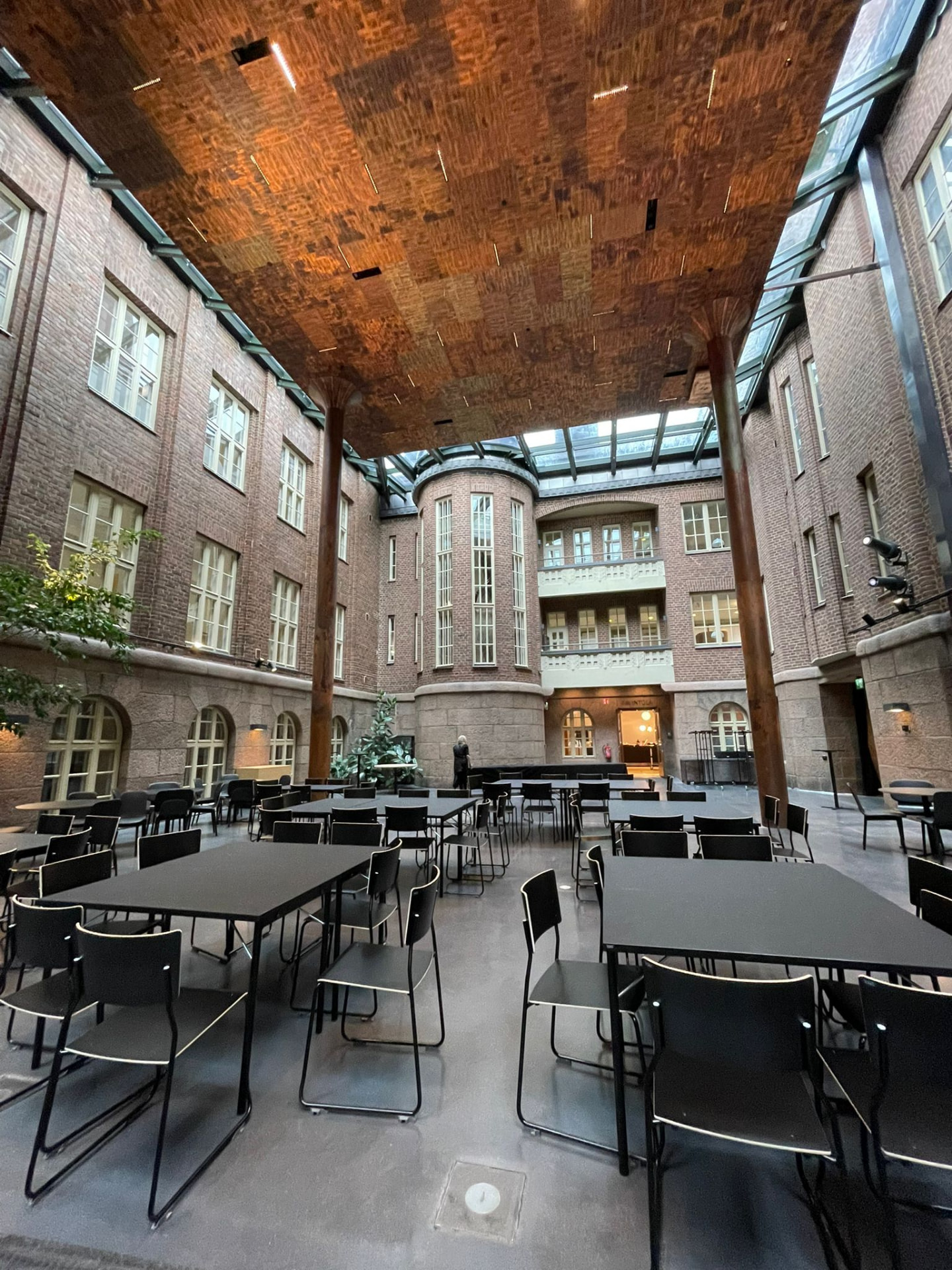 Glass-roofed inner courtyard of Lahti City Hall set with tables and chairs